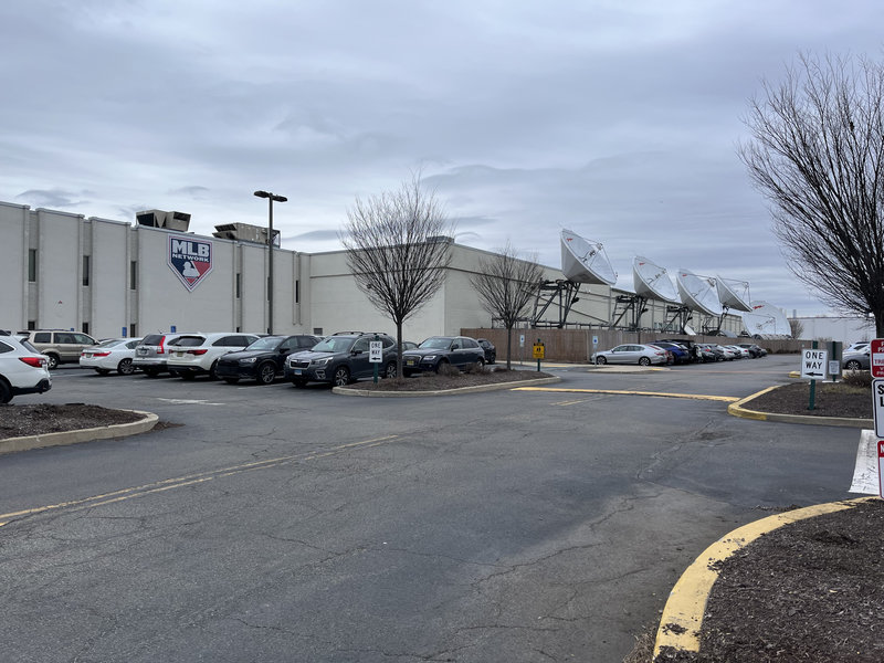 A windowsless building the MLB logo on the side, some satellite dishes on the
         side.
