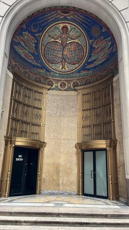 The front of a building, with a title mural on top of the entrance.